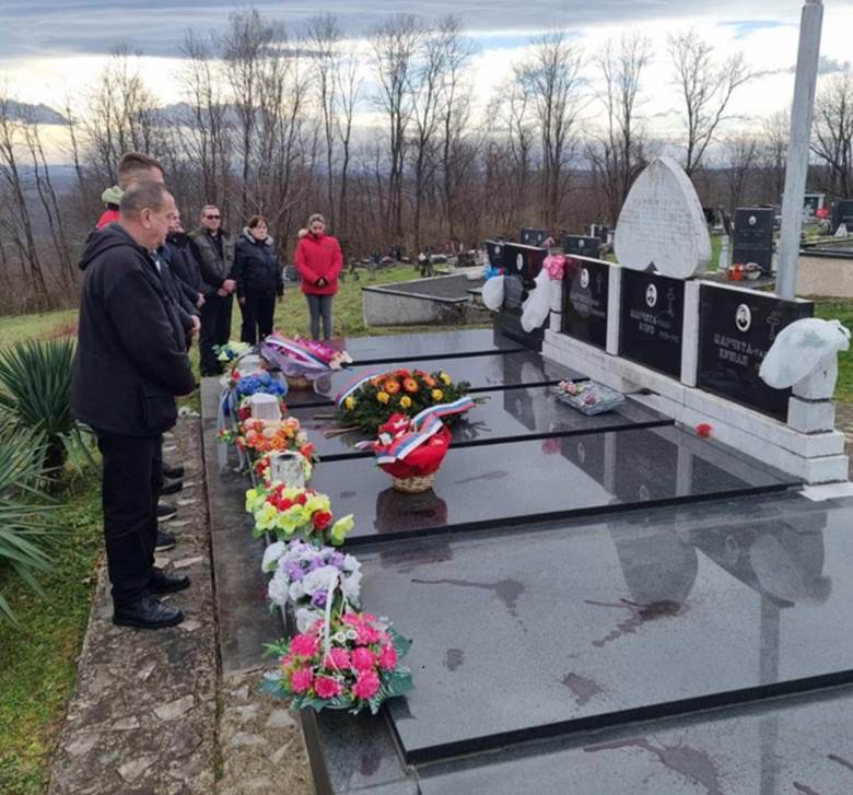 A group of people standing around a graveDescription automatically generated